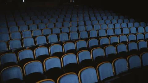 Theater interior with rows of empty blue upholstered seats with wooden frames in 스톡 사진