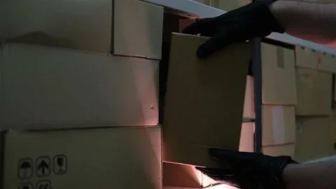 Theft of a box with a parcel in a warehouse. Man hands in gloves steal a box in  Stock Footage 145880166