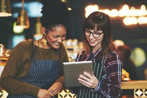 Their cafes menu is an interactive one. two young women using a digital tablet Foto stock