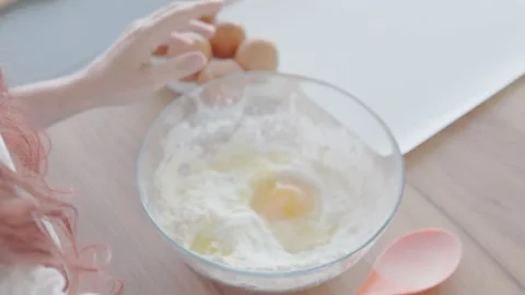 In their cozy kitchen, the baker meticulously cracks eggs into a mixing bowl, a Stock Footage 279922152