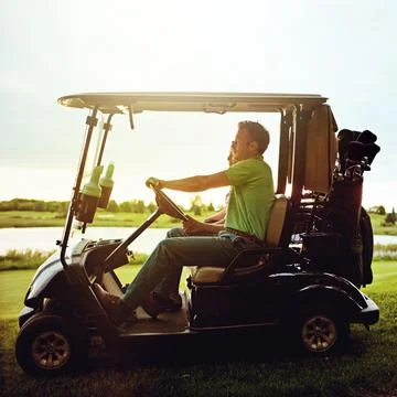 Their first date is right on course. a couple riding in a golf cart on a golf Fotos de archivo
