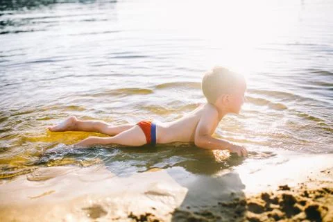 Theme is summer time and rest near the water. Little joyful Caucasian funny boy Stock Photos