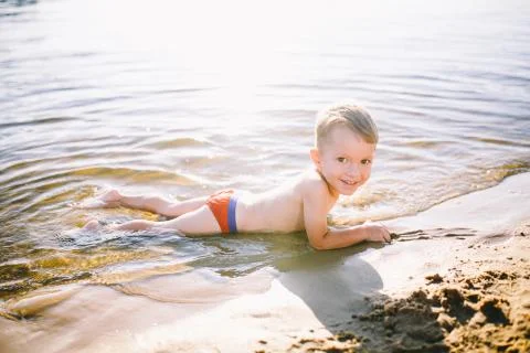 Theme is summer time and rest near the water. Little joyful Caucasian funny boy Stock Photos