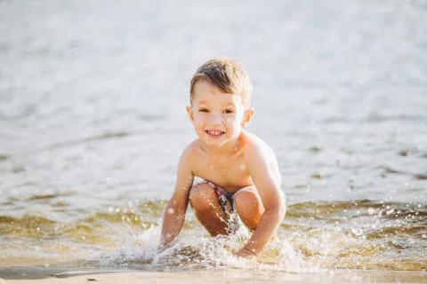 Theme is summer time and rest near the water. Little joyful Caucasian funny boy Stock Photos