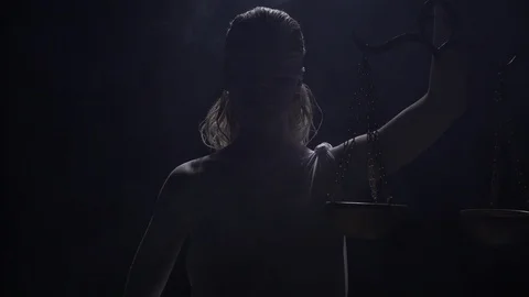 Themis is standing in dramatic lighting with the scales in hand, in the smoke 4k Video stock 112372783