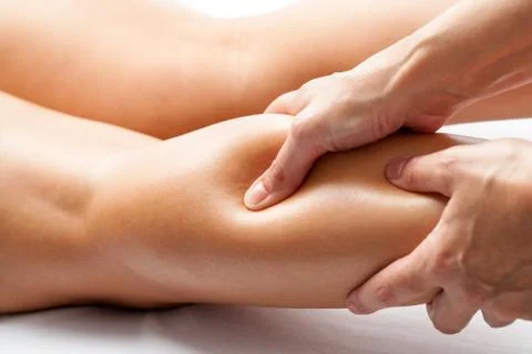 Therapist applying pressure with thumb on female calf muscle. Stock Photos