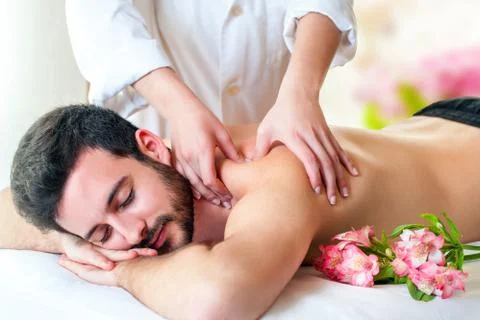 Therapist doing back massage on young man. Stock Photos