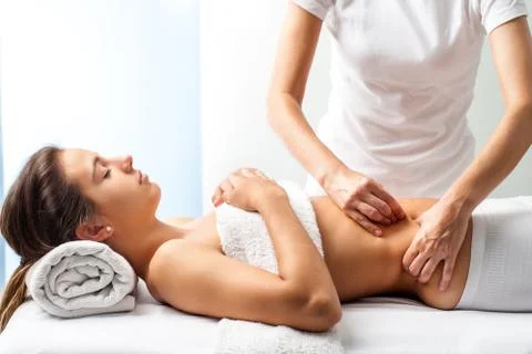 Therapist doing healing massage on female abdomen. Stock Photos