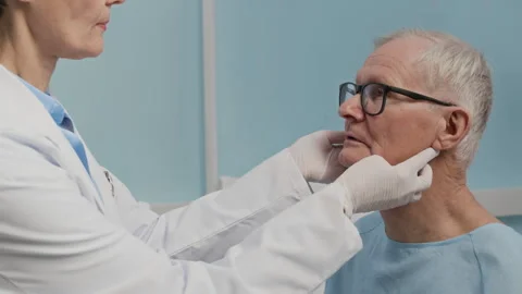 Therapist Examining Lymph Nodes of Aged Patient in Clinic Stock Footage 303877009