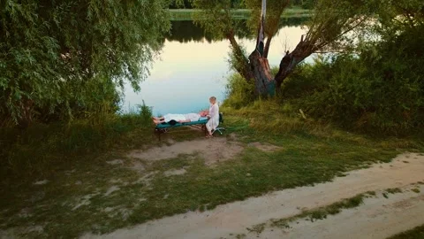 Therapist massaging client head near peaceful lake. Woman delivering relaxing Stock Footage 301993471