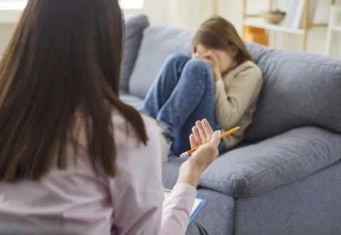 Therapist offering support to crying child during counseling session at home Stock Photos