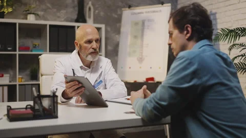 Therapist shows X-ray image on tablet to sad patient, explaining bad diagnosis Stock Footage 342749636