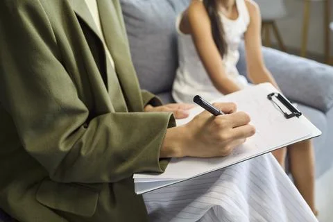 Therapist writing notes on clipboard during child counseling therapy session Stock Photos