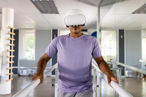 Therapy patient grasping parallel bars while wearing VR headset in therapy room, Stock Photos