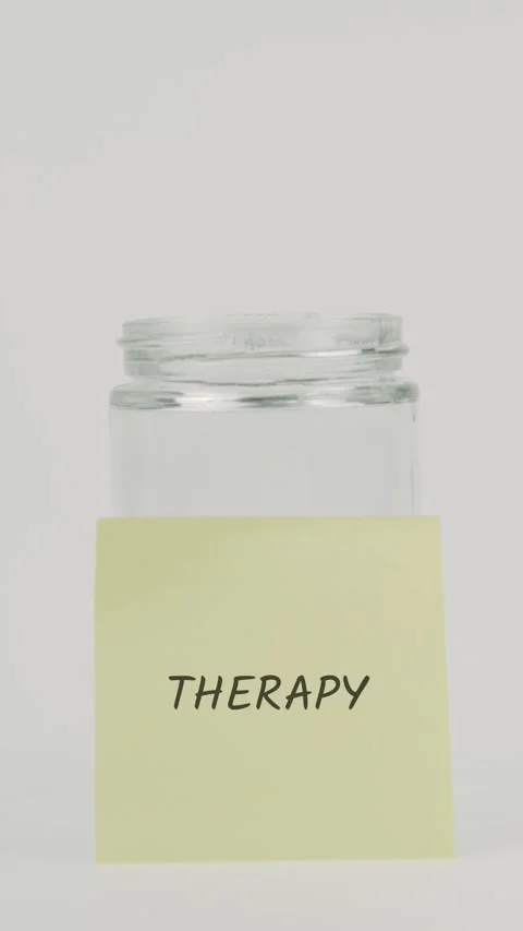 Therapy text or word on yellow sticky note attached to glass jar with hand Stock Footage 311795845
