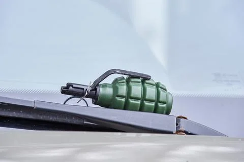 There is an airsoft fragmentation grenade on the windshield wiper of the car Stock Photos