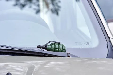 There is an airsoft fragmentation grenade on the windshield wiper of the car Stock Photos