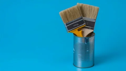 There are brushes and yellow dandelions in a paint can. Stock Footage 309906935