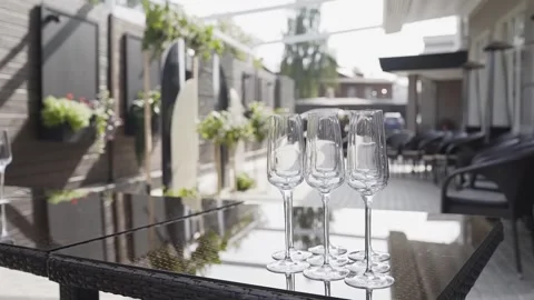 There are empty champagne glasses on a wooden table in the open air. The waiter Stock-Footage 306144779