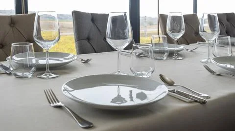 There are empty white plates and cups on the dining table Stock Photos