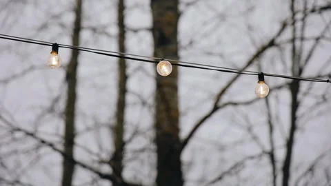 There are light bulbs hanging on a wire in the courtyard Stock Footage 329372651