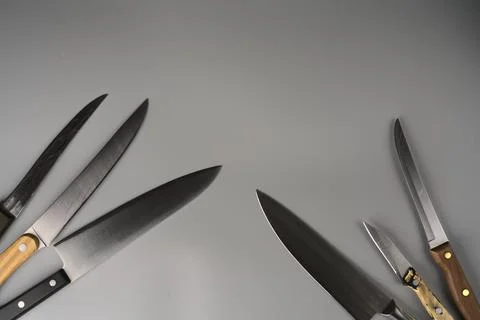 There are many sharp knives of different sizes on a gray background and they Foto stock