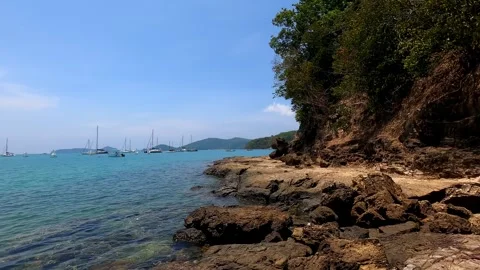 There are many small sailing boats in the sea near a large rock. Stock Footage 243279482