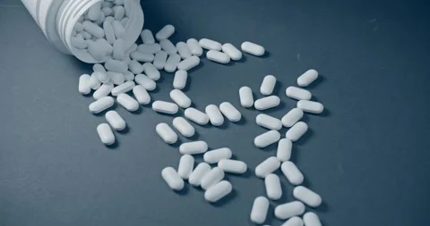 There are scattered white capsules from an open bottle nearby Stock Footage 302901718