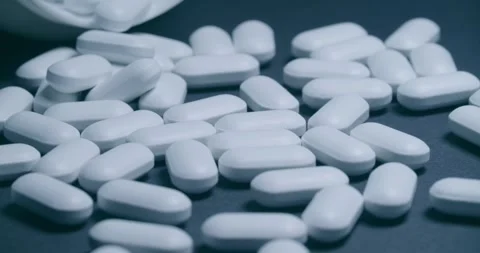 There are scattered white capsules from an open bottle nearby 動画素材 302901992