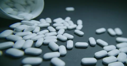 There are scattered white capsules from an open bottle nearby 動画素材 302902031