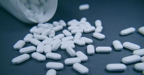 There are scattered white capsules from an open bottle nearby Vidéo 302902104