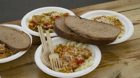 There are several plates with pasta, bread and cutlery on the table. Stock Footage 246941319