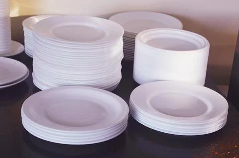 There are several stacks of clean white ceramic plates on the table. Cleani.. Fotos Stock