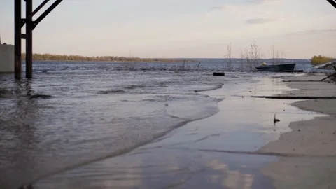 There are small waves on river bank.In the background is a boat. Summer evening. Stock Footage 130729102