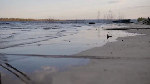 There are small waves on river bank.In the background is a boat. Summer evening. Stock Footage 130729230