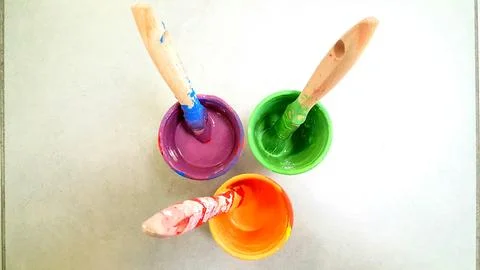There are three cups filled with paint and brushes placed on a table 写真素材