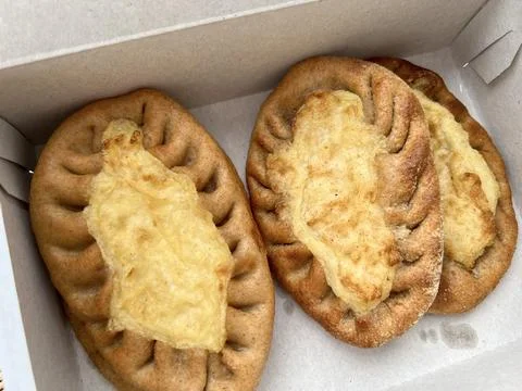 There are three pieces of bread topped with cheese placed in a box Stock Photos