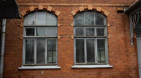 There are two elegantly arched windows located on a red brick building Stock Photos