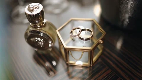 There are two gold wedding rings on a glass casket. Shooting beautiful objects Stock Footage 165493938