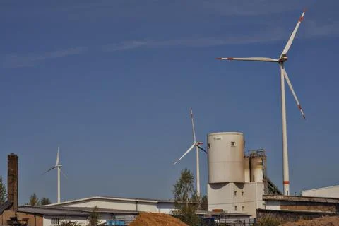 There are two large wind turbines positioned right in front of a building Stock Photos