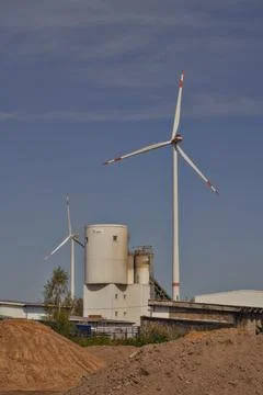 There are two large wind turbines positioned right in front of a building Stock Photos