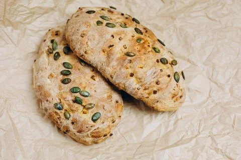 There are two loaves of bread with corn on the paper. Stock Photos