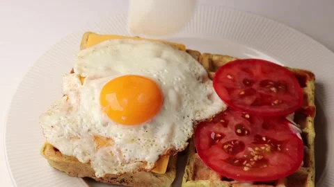 There are two rectangular waffles with tomato slices and a fried egg Stock Footage 294564505
