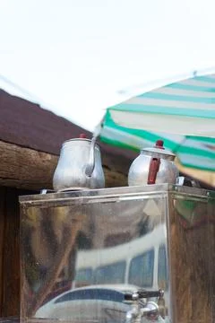 There are two teapots resting atop a container, sheltered under an umbrella Foto stock