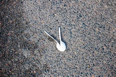 There are two white plastic spoons that are laying on the ground Stock Photos
