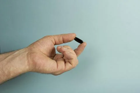 There is a black capsule in the man's hand. Stock Photos