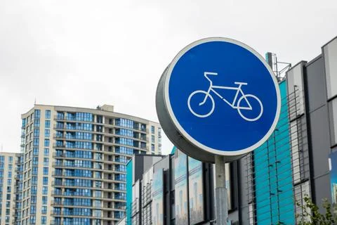 There is a blue traffic sign featuring a bicycle in front of a building Stock Photos