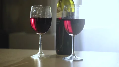 There is a bottle and two glasses of red wine on the table. Stock Footage 154506482