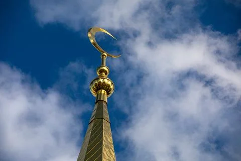There is a clock tower that features a crescent moon ornament atop it Stock Photos