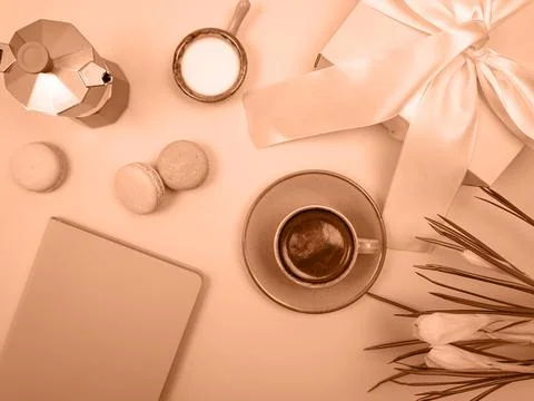 There is a coffee pot on the table, a cup of coffee, a notebook and flowers. The Stock Photos